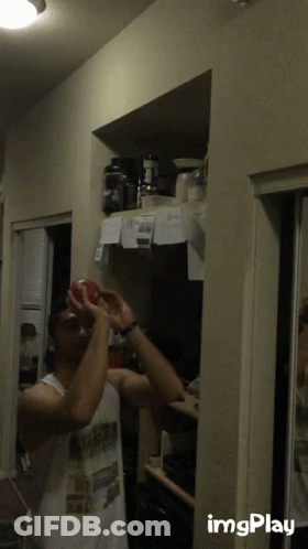 Man In White Tank Top Holding Red Apple GIF
