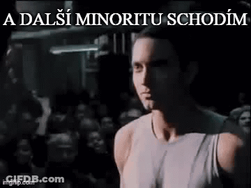 Man In White Tank Top In Front Of Crowd In Dark Room GIF