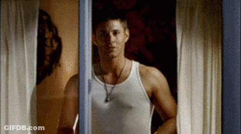 Man In White Tank Top Looking Out Window GIF