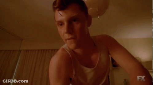 Man In White Tank Top Smiling In Dark Room GIF
