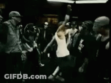 Man In White Tank Top Standing Before Crowd In Dark Room GIF