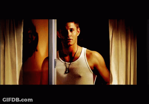 Man In White Tank Top Standing In Front Of Window GIF