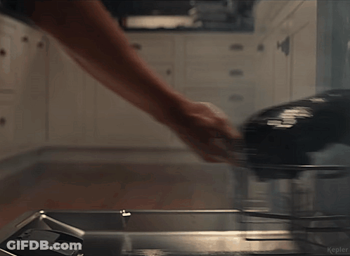 Man In White Tank Top Standing In Kitchen Holding Bottle GIF