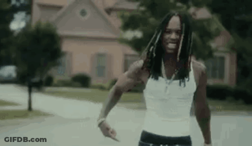 Man In White Tank Top Walking Down Street GIF