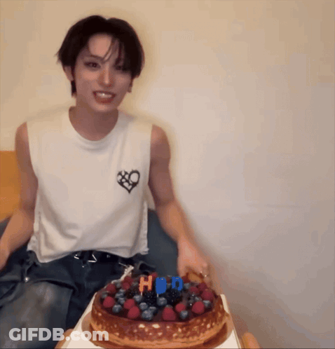 Man In White Tank Top With Heart Sitting Next To HBD Cake GIF