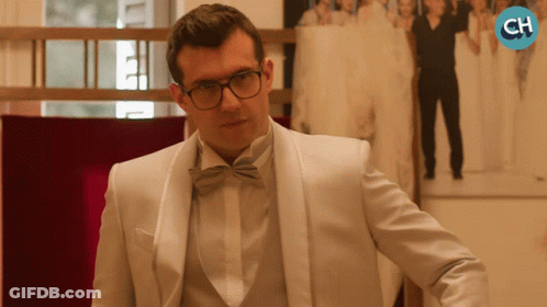 Man In White Tuxedo And Bow Tie In Front Of CH Logo GIF