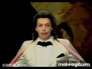 Man In White Tuxedo With Bat On Jacket GIF