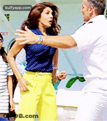 Man In White Uniform Next To Woman In Blue Top And Yellow Pants GIF