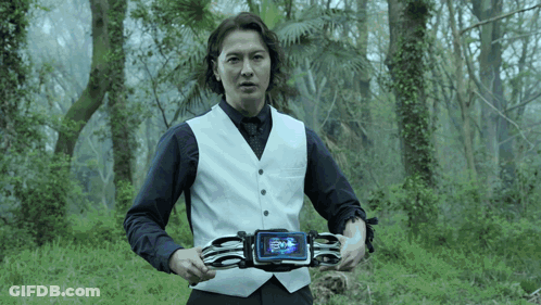 Man In White Vest Holding Device Saying Evil GIF