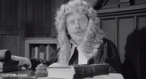 Man In Wig And Glasses At Desk With Book GIF