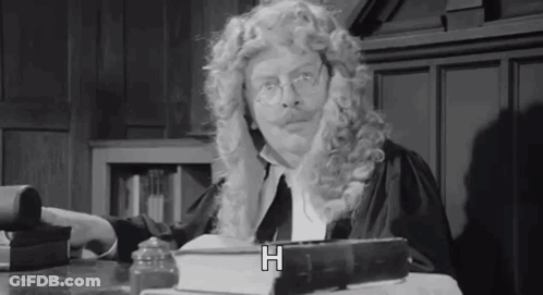 Man In Wig And Glasses Sitting At Table GIF