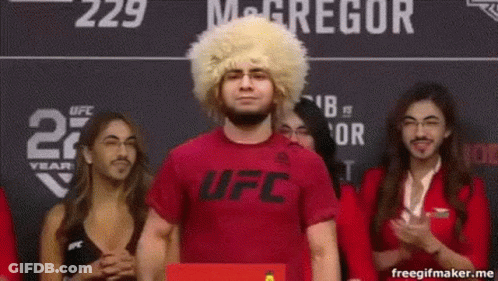 Man In Wig And Red Shirt Standing Before Crowd GIF