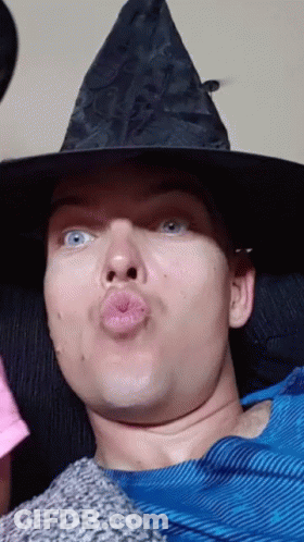 Man In Witch Hat Blowing Kiss GIF