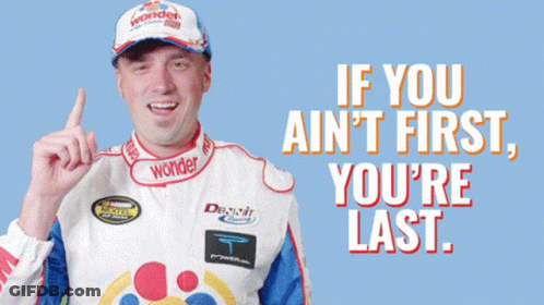 Man In Wonder Hat Points Up Saying If You Ain't First You Last GIF
