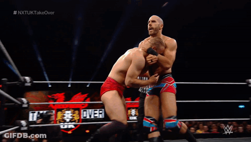 Man In Wrestling Ring With NXTUK Takeover Screen GIF