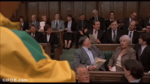 Man In Yellow And Green Jacket With People In Suits GIF