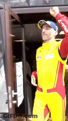 Man In Yellow And Red Racing Suit At Door GIF
