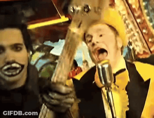 Man In Yellow Hat Singing Into Microphone Holding Guitar GIF
