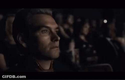 Man In Yellow Hazmat Suit Walking In Crowd GIF