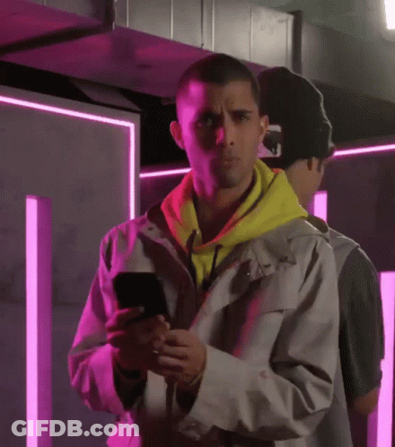 Man In Yellow Hoodie Looking At Phone GIF