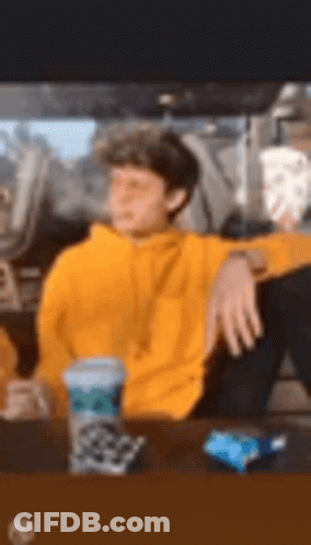 Man In Yellow Hoodie Sitting At Table GIF