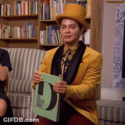 Man In Yellow Jacket And Top Hat Holding Book With Letter D GIF