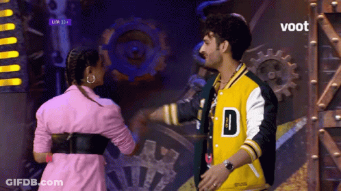 Man In Yellow Jacket D And Woman In Pink GIF