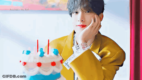 Man In Yellow Jacket Holding Cake With Candles GIF