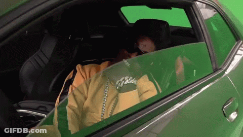 Man In Yellow Jacket In Green Car With Green Screen GIF