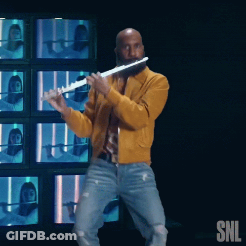 Man In Yellow Jacket Playing Flute In Front Of SNL Logo GIF