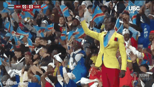 Man In Yellow Jacket With Crowd And Flags GIF