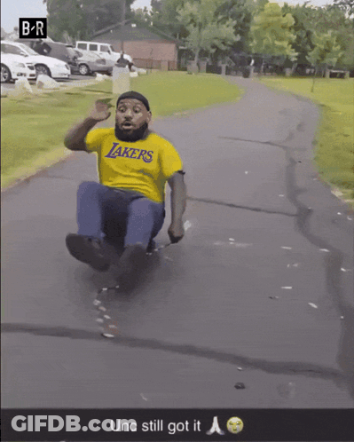 Man In Yellow Lakers Shirt Sliding Down Road GIF