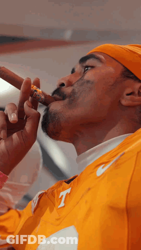 Man In Yellow Nike Shirt With Letter T Smoking Cigar GIF