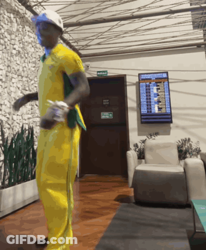 Man In Yellow Outfit Dancing Near Avenida Sign GIF
