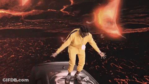 Man In Yellow Outfit Standing On Black Car GIF