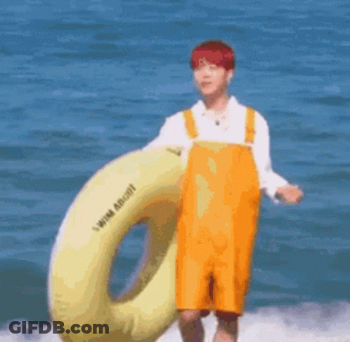Man In Yellow Overalls Holding Life Preserver In Ocean GIF