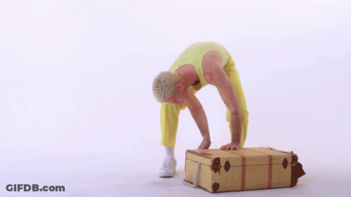 Man In Yellow Pants Bending Over Brown Suitcase GIF