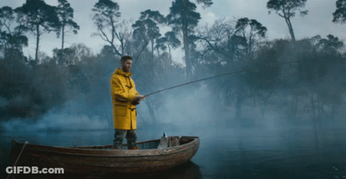Man In Yellow Raincoat Fishing In Boat GIF
