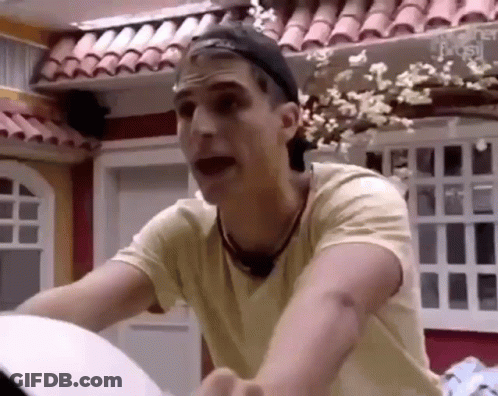 Man In Yellow Shirt And Black Hat Standing In Front Of House GIF