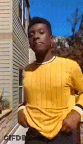 Man In Yellow Shirt And Black Pants Standing In Front Of Building GIF