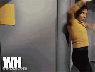 Man In Yellow Shirt And Black Pants Standing In Front Of Door GIF