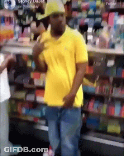 Man In Yellow Shirt And Hat Standing In Front Of Store GIF