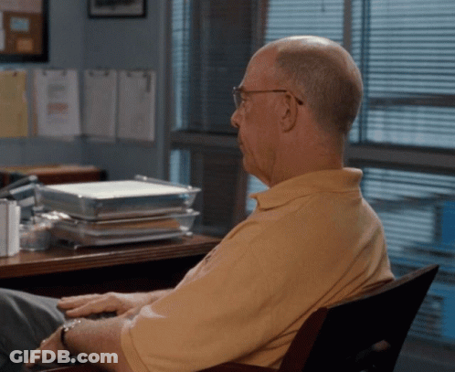 Man In Yellow Shirt At Desk With Stack Of Trays GIF