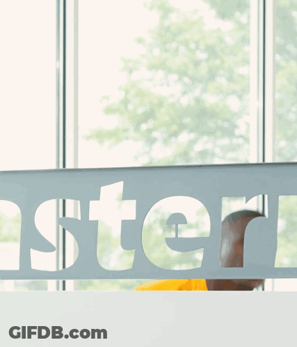 Man In Yellow Shirt Behind Oster Sign GIF