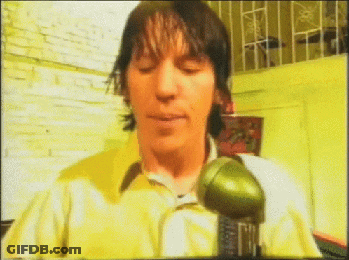 Man In Yellow Shirt Holding Green Object GIF