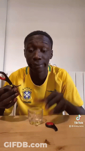 Man In Yellow Shirt Holding Scissors Over Glass GIF