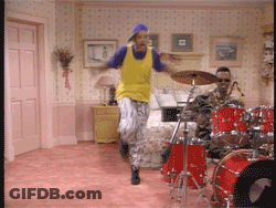 Man In Yellow Shirt Jumping In Front Of Drum Set GIF