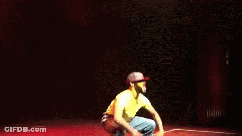 Man In Yellow Shirt Jumping With Arms Outstretched GIF