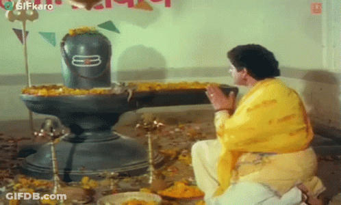 Man In Yellow Shirt Kneeling In Front Of Shiva Statue GIF
