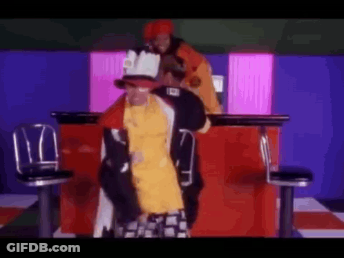 Man In Yellow Shirt Next To Man In Red Jacket GIF